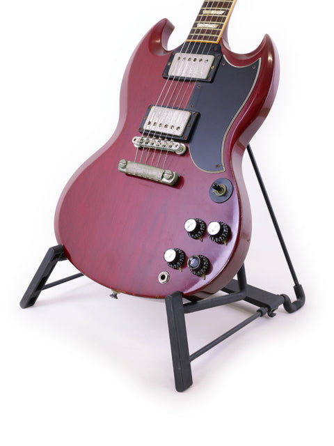 A striking red electric guitar, a Gibson SG '61 Reissue from 1988, elegantly positioned on a stand, ready for performance.