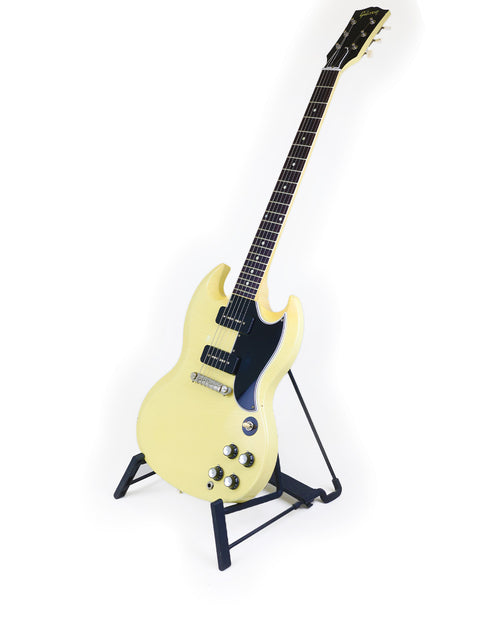 A striking yellow electric guitar, the Gibson Custom ‘63 SG Special, elegantly displayed on a stand.