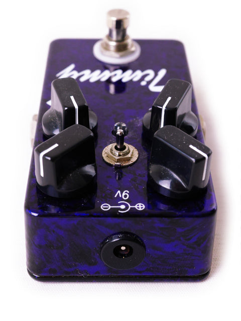 A vibrant purple and black guitar pedal, the Paul Cochrane 'Timmy' overdrive, equipped with four control knobs.