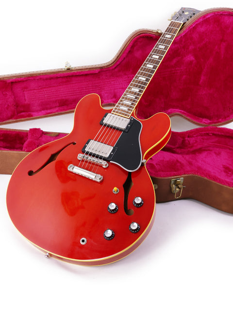 A vibrant red Gibson ES-335 guitar resting in a stylish pink case, highlighting its classic design and custom features.