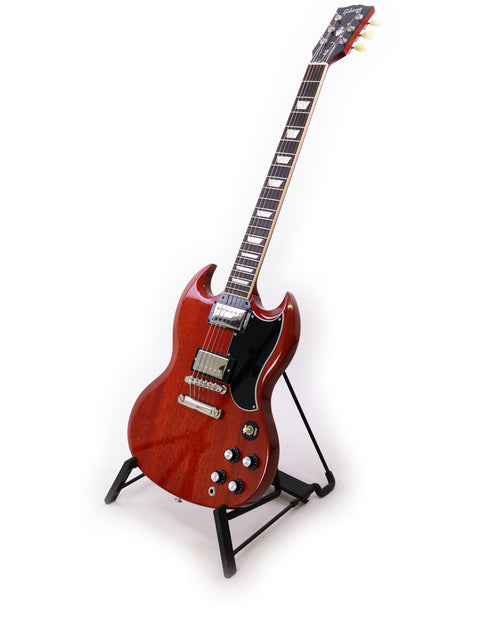 A vibrant red Gibson SG Standard ‘61 guitar displayed on a stand, contrasting beautifully with a plain white backdrop.