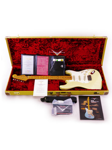 A white Fender Ltd Custom 50s Journeyman Stratocaster guitar securely housed in a case, surrounded by additional items.