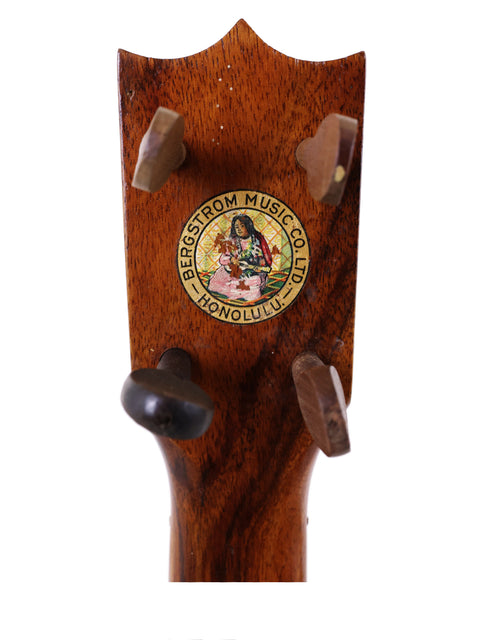 An antique Kumalae Style 2 ukulele, crafted in 1913, displaying a unique sticker on its polished wooden finish.