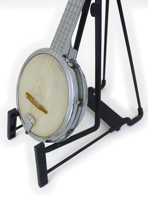 Banjo resting on a black stand against a white background.