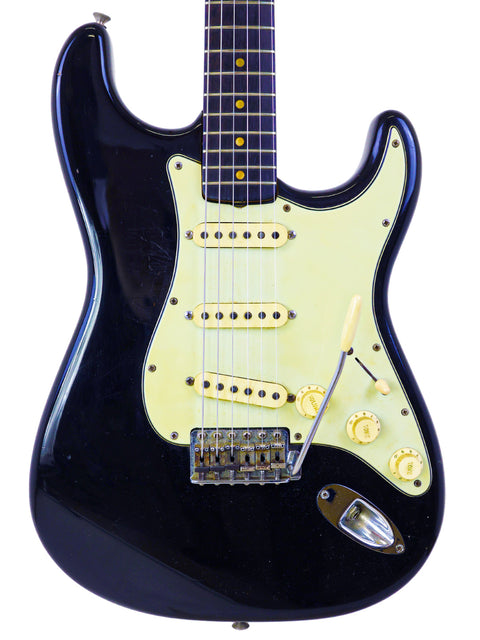 Black electric guitar, a 1963 Fender L-Series Stratocaster, featuring a striking white pickguard for a classic look.