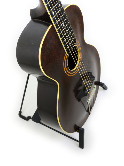 Classic 1920 Vintage Gibson L-1 guitar on a stand, highlighted by a stark white background for a timeless look.