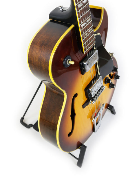 Classic 1970s Gibson ES-175D guitar displayed on a stand, set against a pristine white backdrop for a striking visual.