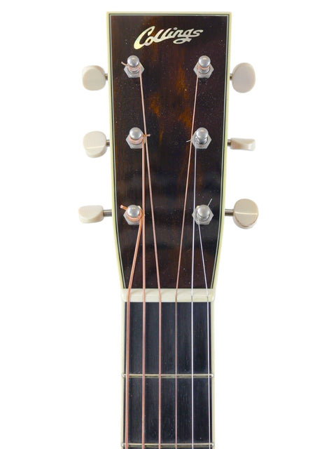 Close-up of a guitar headstock with tuning pegs and the name "Collings" on a white background.
