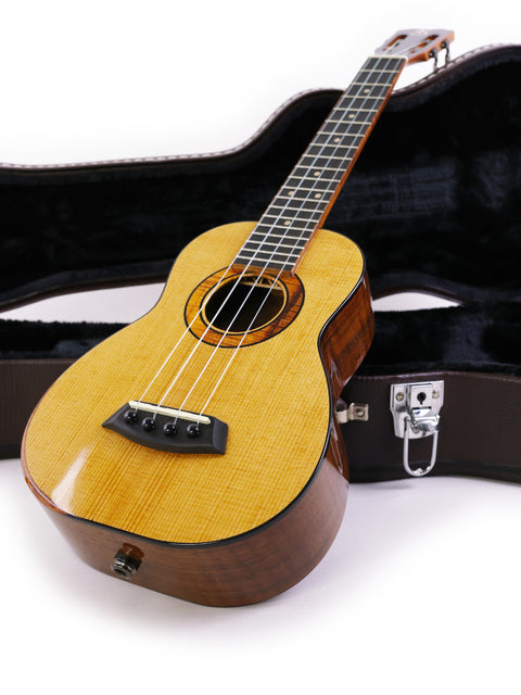 Displayed on a white surface, a Kanile’a Platinum Limited Edition Super Concert Ukulele is nestled in its case.