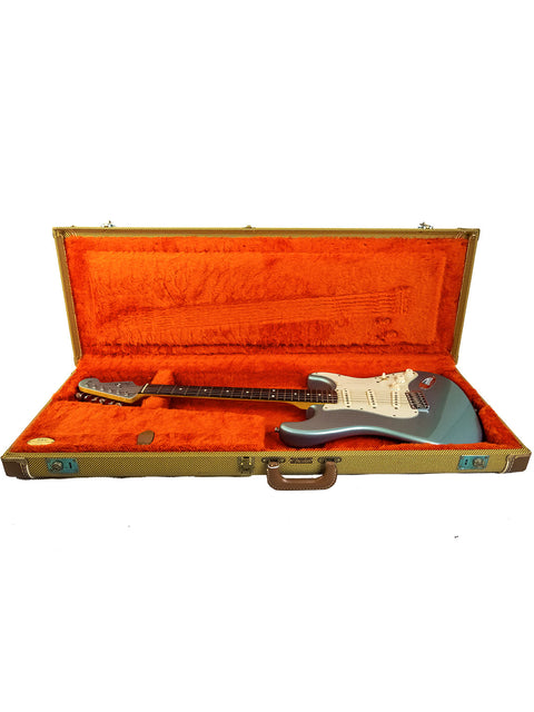 Electric guitar in an open case with red lining.