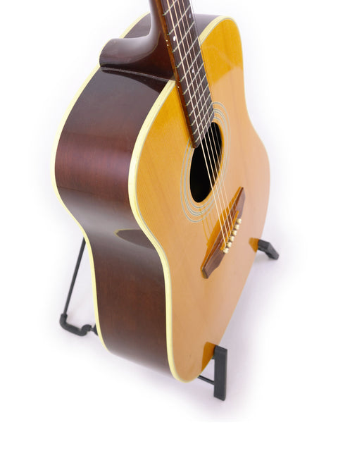 Elegant Guild D-40 guitar from 1989 on a stand, perfectly presented against a bright white background for a striking look.