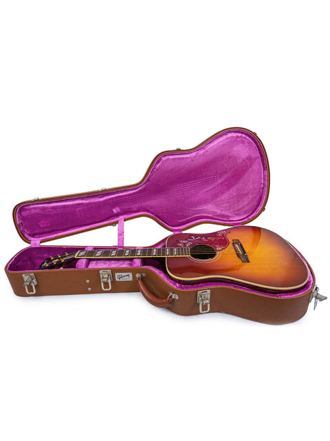 Inside a case, two guitars with a sunburst finish are displayed, one being a 2012 Gibson Hummingbird True Vintage.