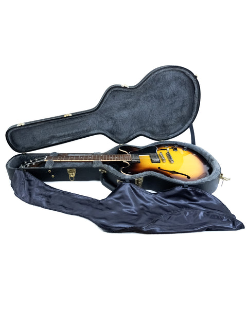 Inside a guitar case, a Gibson Custom ES-335 with dot inlay, crafted in the USA in 2012, is securely stored.