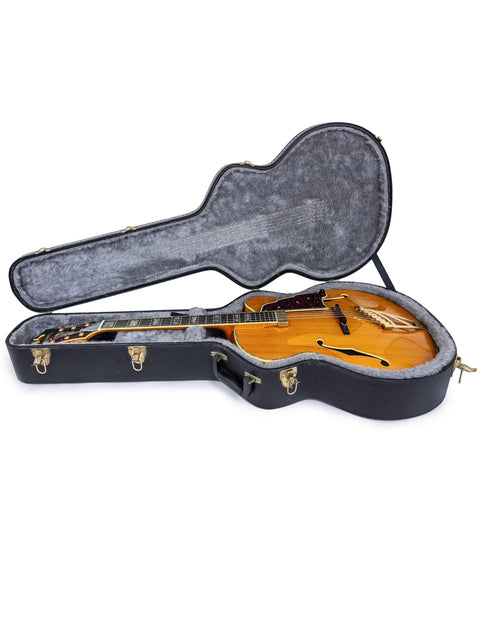 Inside a sleek guitar case lies a D’Angelico New Yorker Series Excel EXL-1DP, highlighting its craftsmanship and beauty.