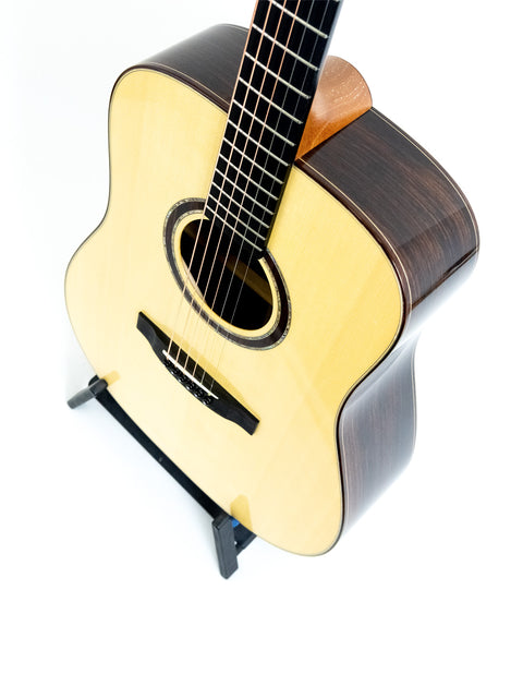 Lakewood D-32 Dreadnought guitar displayed on a stand, set against a bright white background, highlighting its craftsmanship.