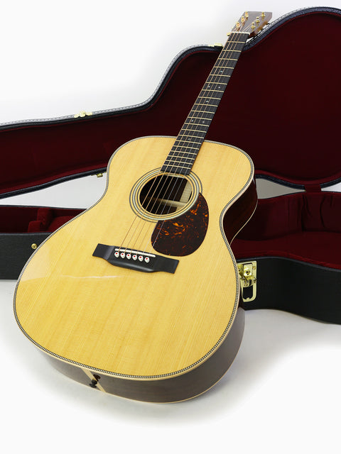 Martin 000-28 Modern Deluxe guitar resting in its case against a white background, showcasing its elegant design.