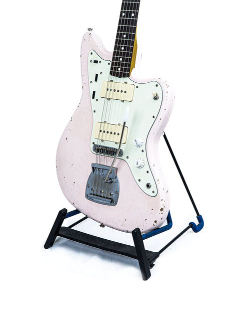 Rittenhouse JM-63 guitar in pink, elegantly displayed on a black stand, highlighting its unique style and craftsmanship.