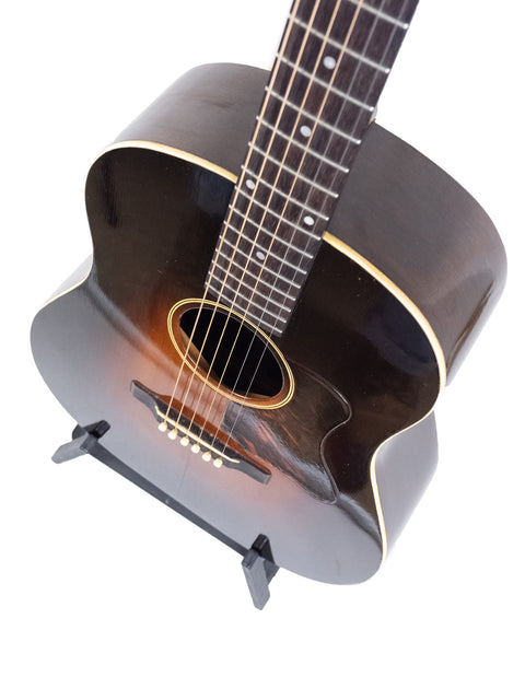 Vintage Gibson Roy Smeck Stage De Luxe guitar resting on a stand, set against a plain white background.