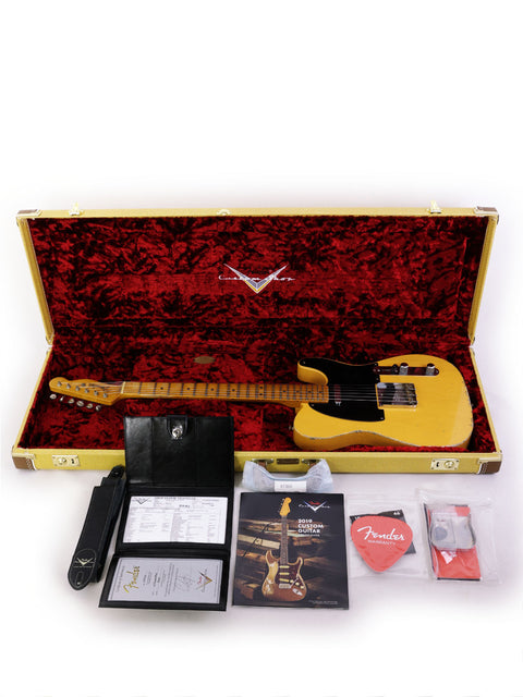 Yellow guitar case featuring a Fender Carlos Lopez Masterbuilt Nocaster and various guitar accessories inside.