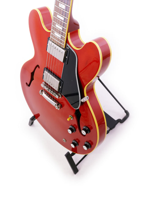 red Gibson ES-335 Block guitar from 1963 rests elegantly on a stand, showcasing its classic design and craftsmanship.