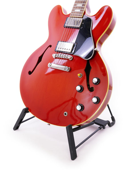striking red Gibson ES-335 Block guitar displayed on a stand, with a minimalist white background highlighting its features.