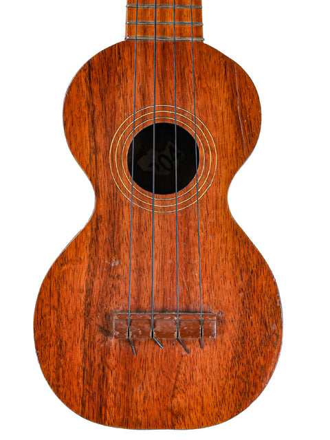 A 1920s Kumalae ukulele with a rich wooden body and a sleek black pick, representing classic Hawaiian musical heritage.