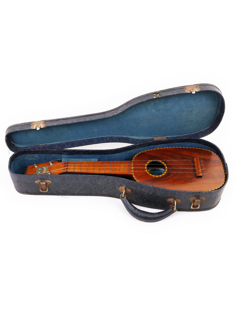 A 1928 Kamaka Pineapple Style #3 ukulele in its case, set against a pristine white background.