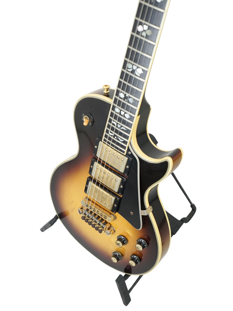 A 1978 Gibson Les Paul Artisan guitar featuring a sunburst finish, elegantly positioned on a stand.