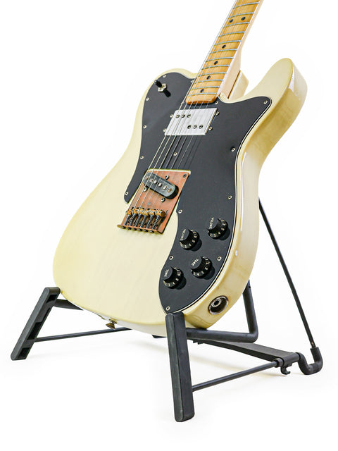 A 1978 white Fender Telecaster Custom guitar displayed on a stand, showcasing its elegant black pick guard.