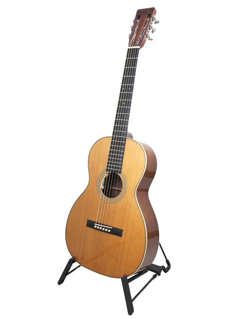 A 2011 Martin 0-28VS guitar elegantly positioned on a stand with a white backdrop.
