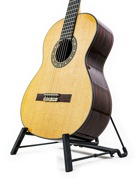 A 2019 José Ramírez Estudio 3 classical guitar elegantly positioned on a stand, set against a stark white background.