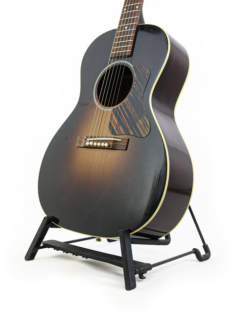 A black Gibson 30s L-00 True Vintage acoustic guitar from 2014, elegantly positioned on a stand for display.