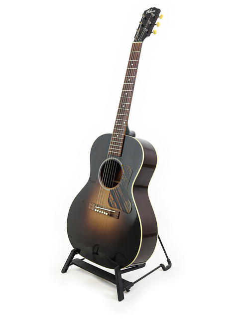 A black acoustic guitar displayed on a stand, featuring the Gibson 30s L-00 True Vintage, made in the USA in 2014.