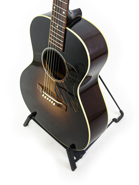 A black acoustic guitar resting on a stand, representing the Gibson 30s L-00 True Vintage, crafted in the USA, 2014.