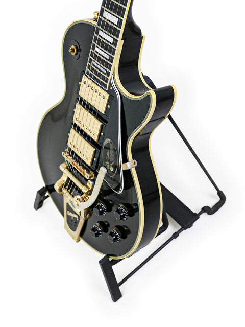 A black and gold Gibson Custom Jimmy Page Les Paul guitar resting on a stand, representing luxury and musical excellence.