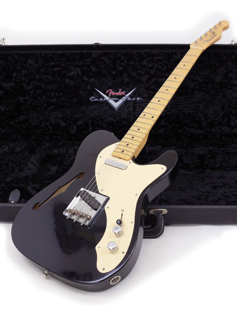 A black electric guitar, the 2005 Fender Custom Shop Telecaster Thinline, nestled in its protective case.