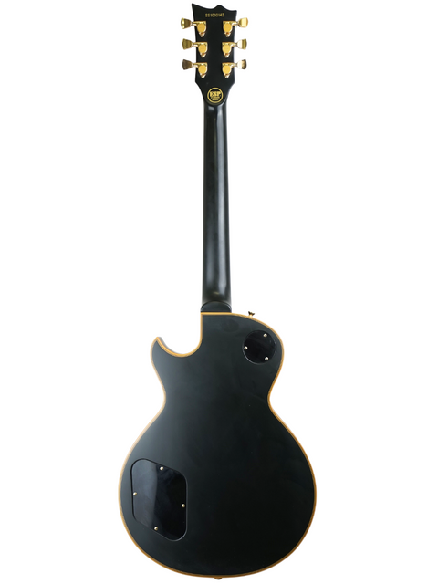 A black electric guitar with gold hardware against a white background.
