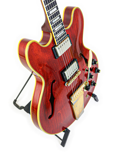 A classic red Gibson ES-355 Stereo guitar from 1967, beautifully positioned on a black stand for a timeless look.