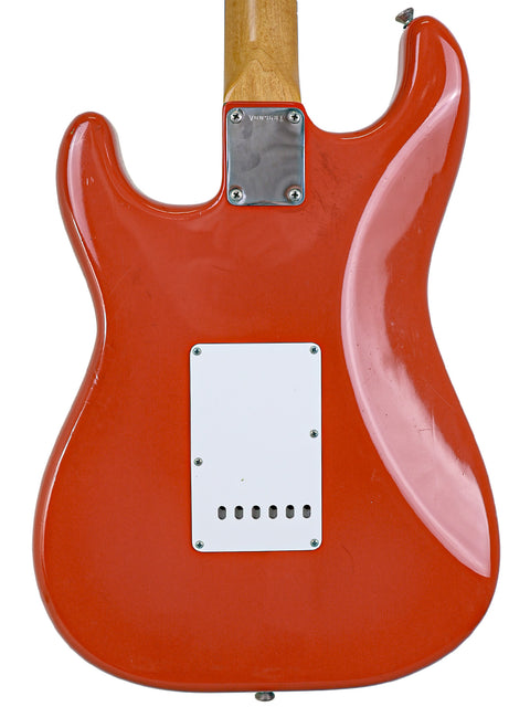 A classic red electric guitar with a wooden body, embodying the timeless look of a 1982 Fender AVRI ‘62 Stratocaster.