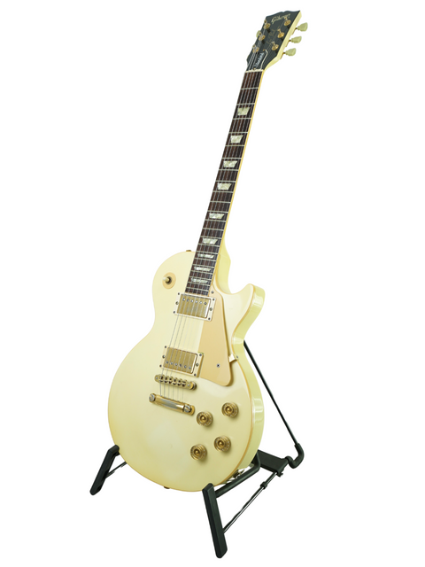 A classic white electric guitar, the 1989 Gibson Les Paul Standard, resting on a stand for display.