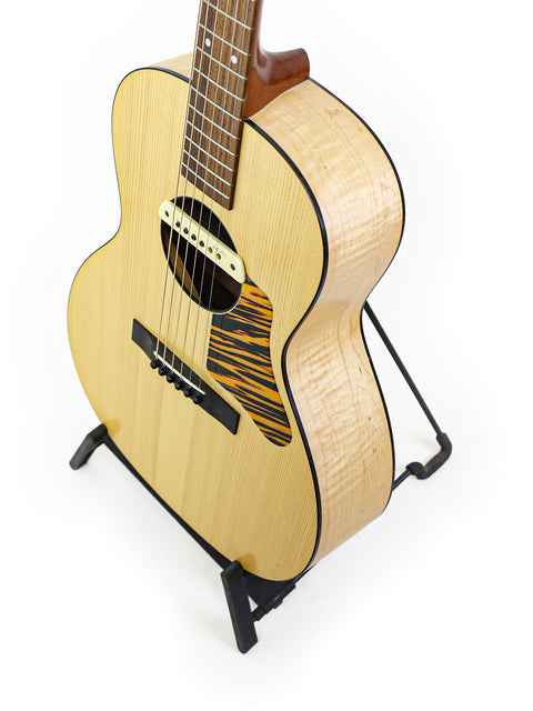 A compact Waterloo WL-14 X Scissortail acoustic guitar displayed on a stand, highlighting its beautiful wood finish.