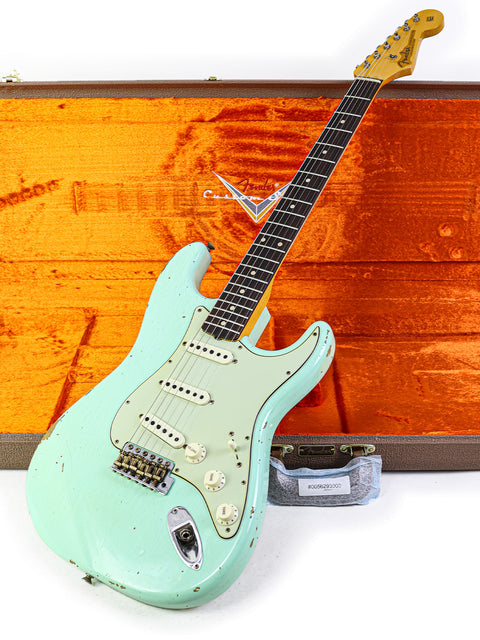 A green Fender guitar, the ‘59 Stratocaster Relic by Yuriy Shishkov, displayed with its case and a wooden box.