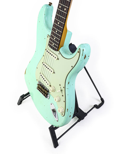 A green guitar, the Fender Yuriy Shishkov Master Built ‘59 Stratocaster Relic, resting on a sleek black stand.