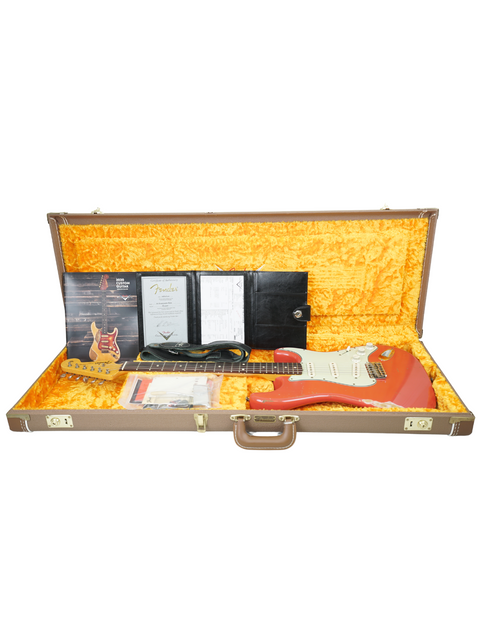 A guitar case opens to reveal a Fender Kyle McMillin Masterbuilt 1960 Stratocaster Relic, blending elegance and artistry.
