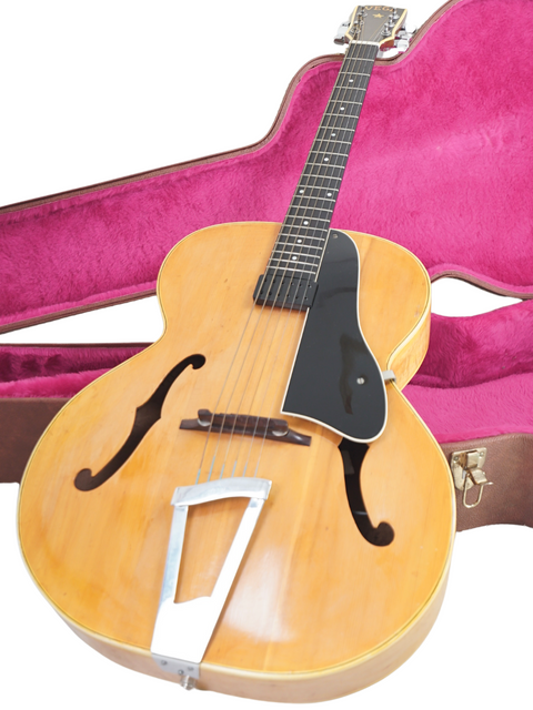 A pink case holds a vintage Vega C-66 guitar from 1940, blending classic style with a pop of color.