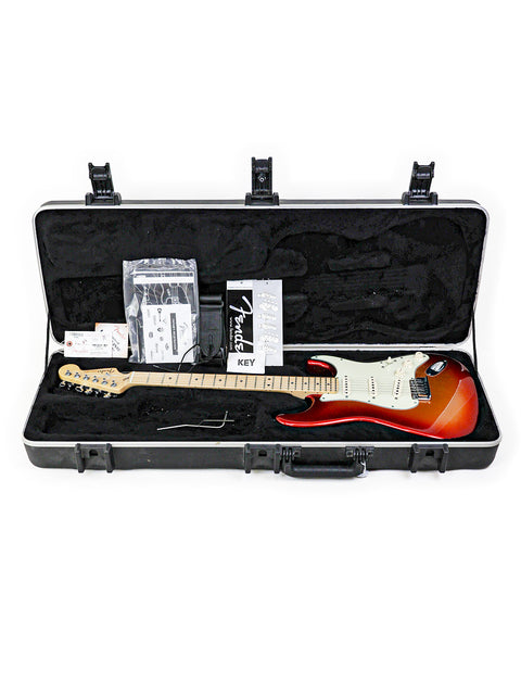 A red and white electric guitar in a black case with accessories.