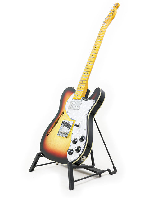 A sleek Txxx Custom Thinline '72 Partscaster guitar resting on a stand, set against a bright white background.