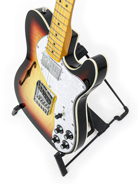 A sleek Txxx Custom Thinline '72 Partscaster guitar showcasing a vibrant black and orange sunburst finish from 2022.