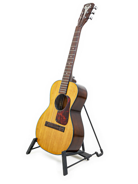 A small Kay K113 parlour guitar from 1966-68 displayed on a stand, with a minimalist white background highlighting its features.