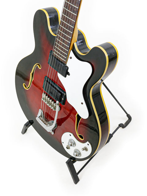 A striking black and red 1967 Mosrite Celebrity III guitar resting on a stand, showcasing its vintage charm.